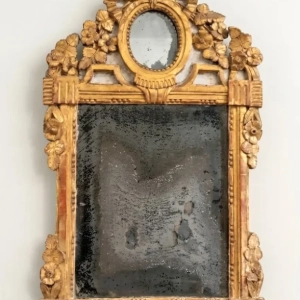An attractive Louis XVI, gilded wood mirror surmounted by ribbons, foliage, flowers around an inset oval mirror. Original mercury glass. 18th century.