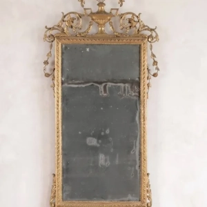 A finely carved Italian giltwood mirror, surmounted with a two handled urn, with ribbons, beads and richly carved floral sprays. Original distressed mirror. 18th C.