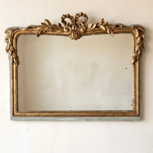 A charming Louis XVI style mirror, decorated with a bow and leaves. Original glass. Repair to bow, minor chips and flaking. Early 20th century.