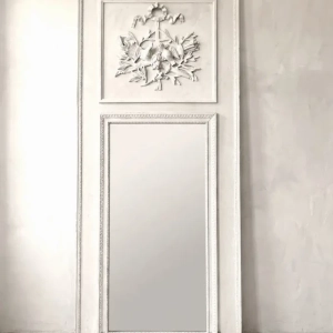 A large painted trumeau mirror with relief decoration. The top panel is decorated with a trophy with a ribbon, birds and quivers of arrows