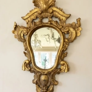 An attractive carved and gilded wooden framed mirror. The pediment is openwork with foliage and facing scrolls. Italy, 18th century.