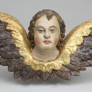 A large baroque putti head and stylized wings. Carved wood, painted and partly gilded. South Germany, circa 1750.